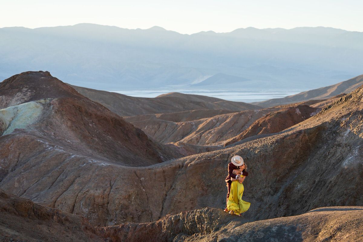 A couple embraces in desert mountains as the sun sets in Death Valley National park