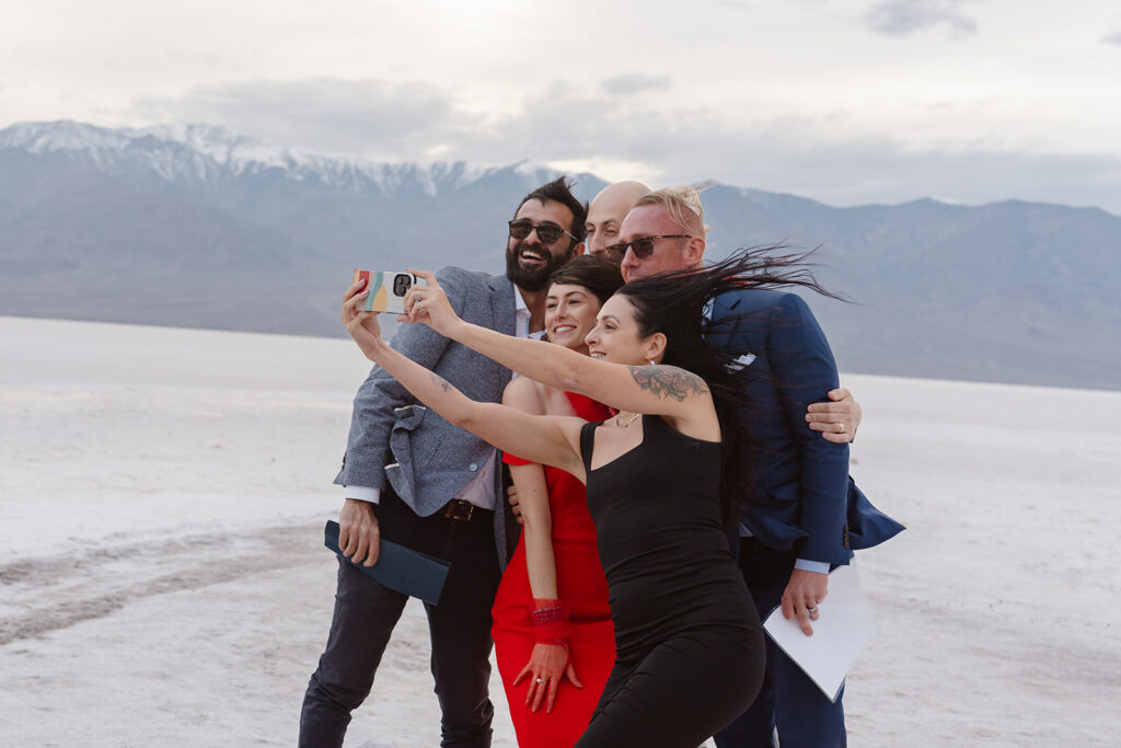a group of friends smile for a selfie at an outdoor elopement