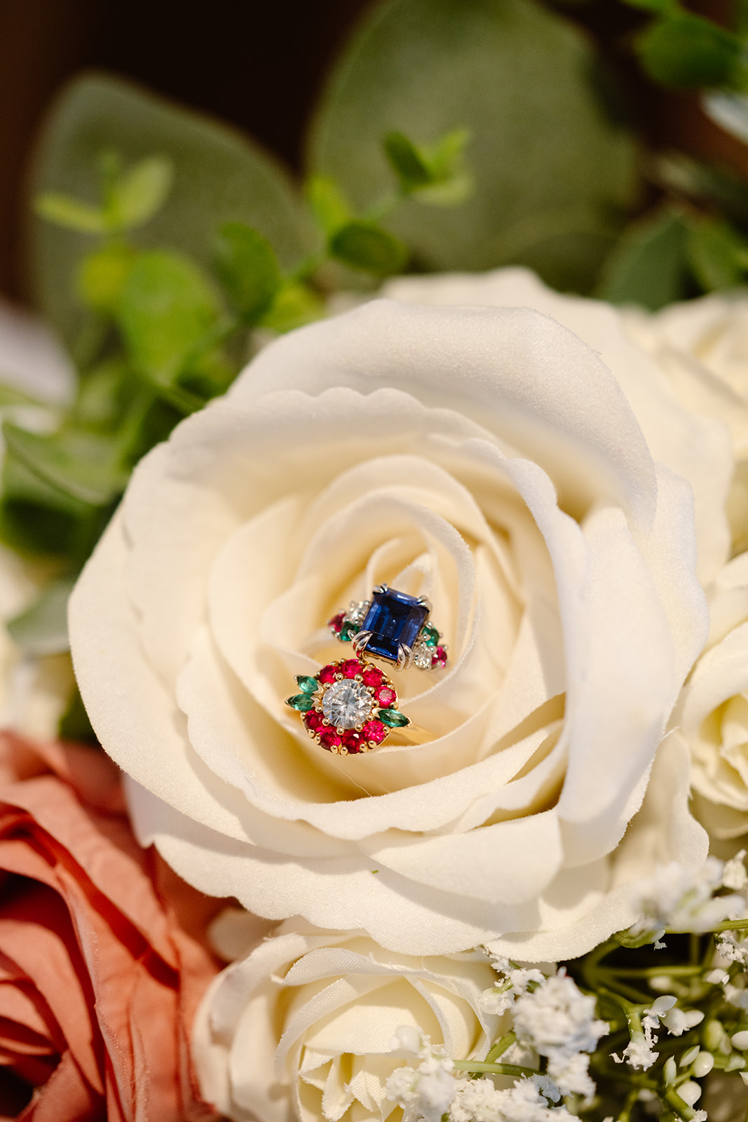 two colorful wedding rings are nestled together in a white rose