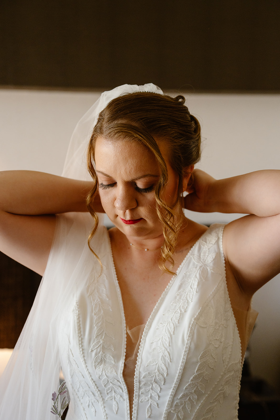 a bride clasps her necklace while getting ready for her queer elopement