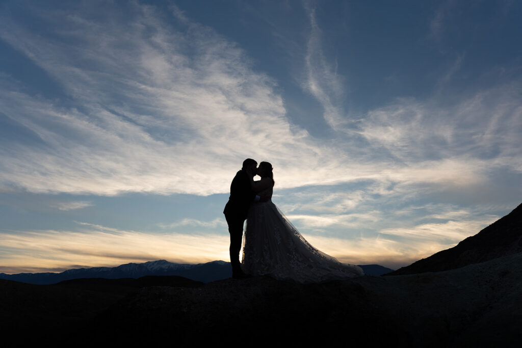 A silhouette of a couple kissing as the sun sets behind them